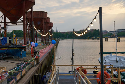 Boats moored at harbor against sky during sunset