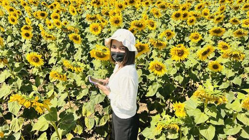 Young woman standing amidst sunflowers