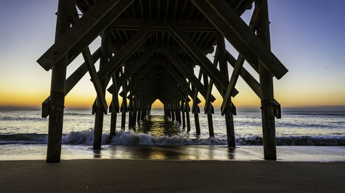 Pier over sea against sky during sunset