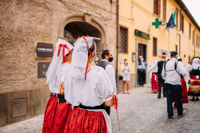 Rear view of people standing on street in city
