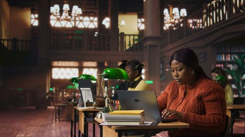 Side view of young woman using laptop at cafe