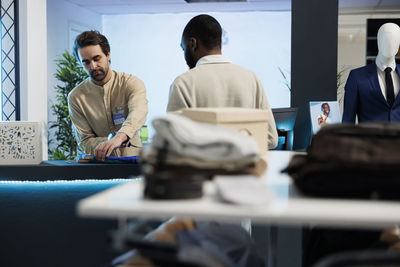 Rear view of man using digital tablet while sitting in office