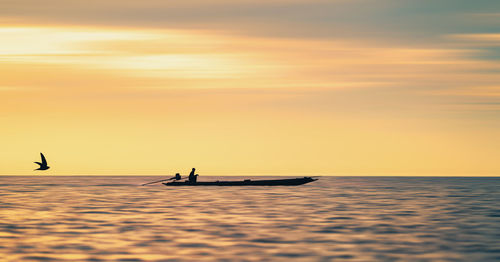 Silhouette person in sea against sky during sunset