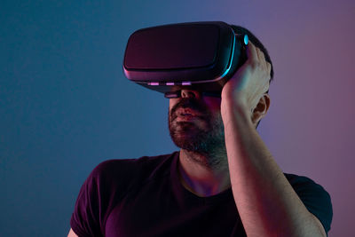 Man using virtual reality simulator against colored background