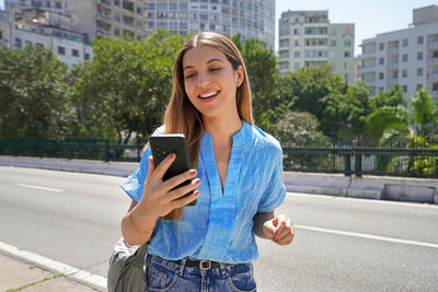 Smiling brazilian girl using smartphone on minhocao highway on sunday, sao paulo, brazil