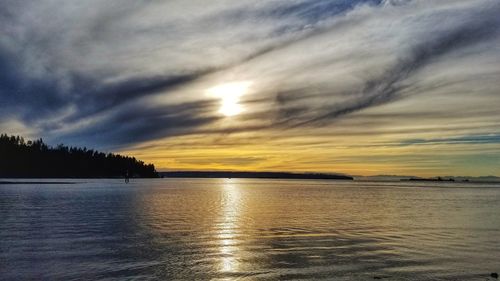 Scenic view of sea against dramatic sky during sunset