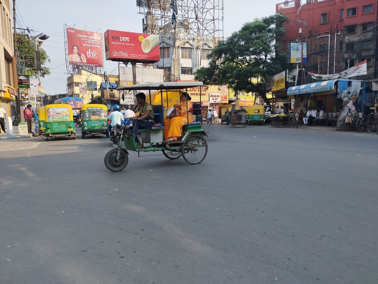 city, transportation, architecture, street, mode of transportation, road, building exterior, rickshaw, city street, city life, built structure, taxi, jinrikisha, car, land vehicle, infrastructure, travel, sign, travel destinations, bicycle, vehicle, motor vehicle, day, traffic, motion, outdoors, adult, nature, lane, town, store, person, on the move, driving, neighbourhood, urban area, downtown, men, sky, motorcycle, building, tourism, communication, lifestyles, public transportation, group of people, transport