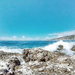 View of rocky beach against blue sky