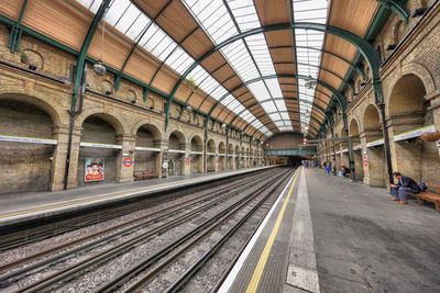 Man sitting on bench at railroad station platform