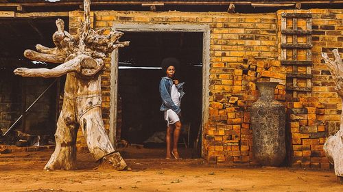 Portrait of young woman standing at doorway of abandoned building