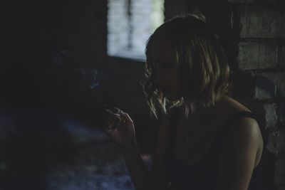 Young woman smoking cigarette in darkroom