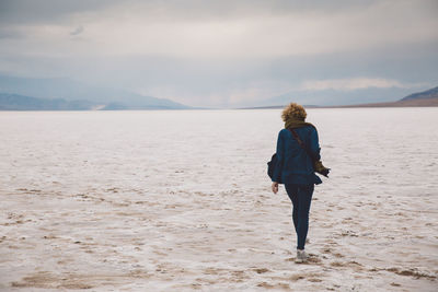 Rear view of young woman walking on sand