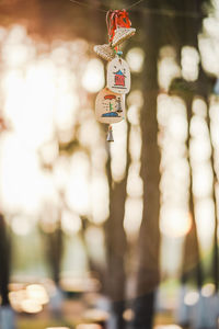 Close-up of cross hanging wind chimes against blurred background