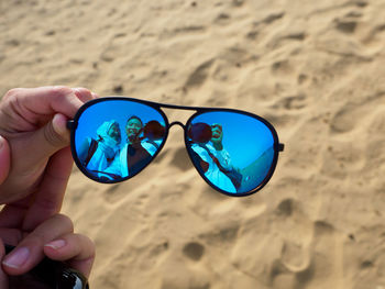 Close-up of hand holding sunglasses at beach