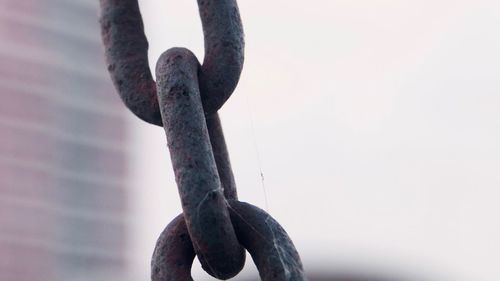 Close-up of rope tied on metal chain against clear sky