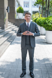 Handsome businessman in grey suit standing on the street. high quality photo