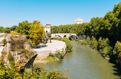 Tiber island by river against sky on sunny day