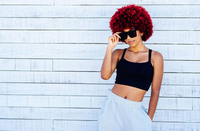 Woman looking at camera while standing against wall