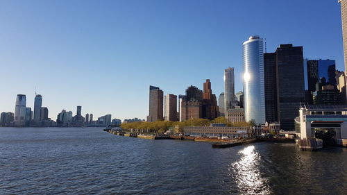 City buildings by river against sky