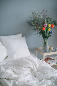 Close-up of flowers in vase on bed