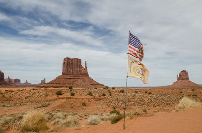 The rock formations of the monument valley in desert against sky with the america flag 