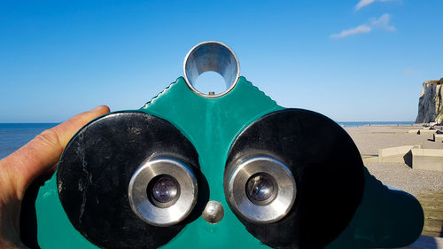 Close-up of human hand holding sea against clear sky