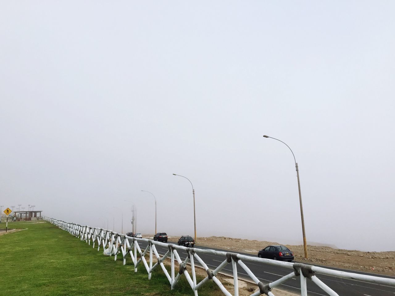 clear sky, copy space, transportation, road, railing, grass, field, landscape, the way forward, day, empty, nature, street light, tranquility, tranquil scene, fence, outdoors, mode of transport, no people, sky