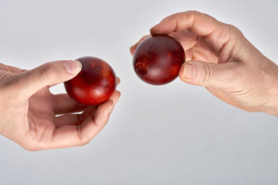 Close-up of hand holding strawberry over white background