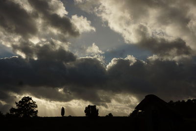 Low angle view of storm clouds over silhouette landscape