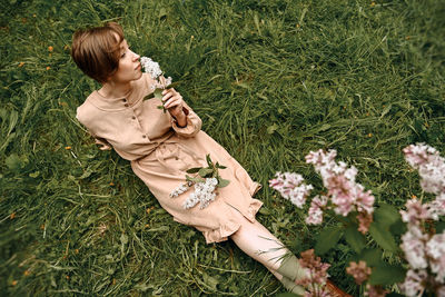 Woman holding flower while sitting outdoors