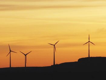 Wind turbines on landscape at sunset