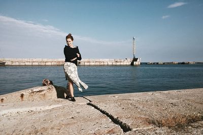 Portrait of woman standing by harbor against sky