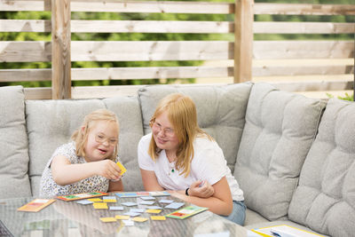 Girls sitting on sofa and playing cards