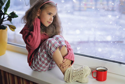 Girl looking away while sitting on table