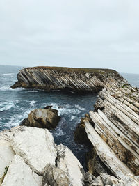 Rocks on shore by sea against sky