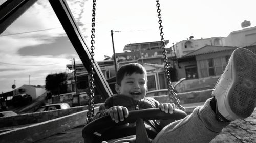 Boy enjoying while sitting in chain swing