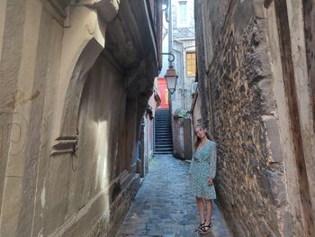 Rear view of woman on alley amidst buildings