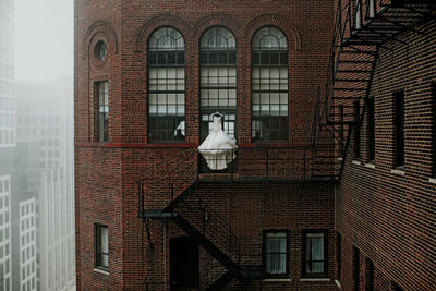 Wedding dress hanging by fire escape of building in city