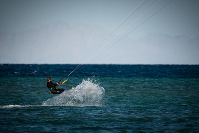 Man kiteboarding over sea against sky