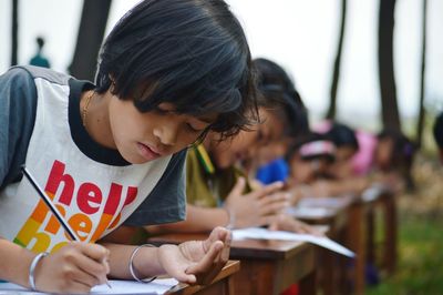 Close-up of girl writing in book on bench