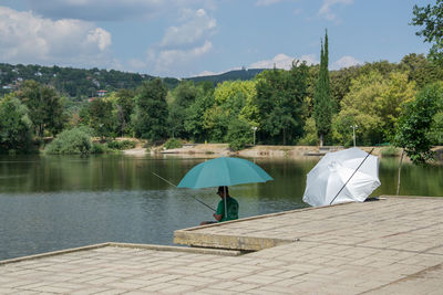 Rear view of person by lake against sky