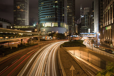 Light trails on road amidst buildings in city at night