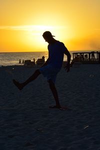 Silhouette woman on beach against sky during sunset