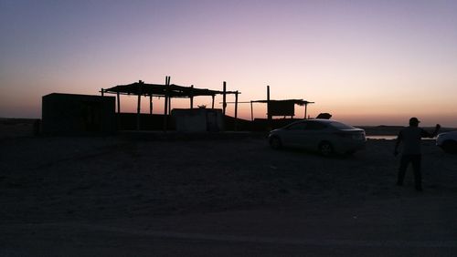 Silhouette man on car against sky during sunset