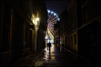 Full length of people walking on illuminated street at night