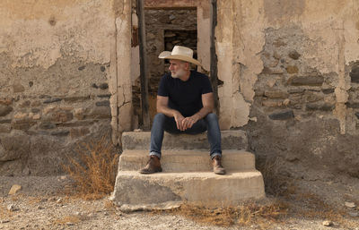 Adult man in cowboy hat and shirt sitting on step