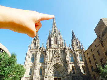 Optical illusion of person touching barcelona cathedral against clear sky