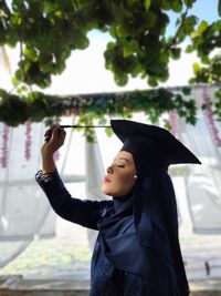 Side view of woman wearing graduation gown standing outdoors