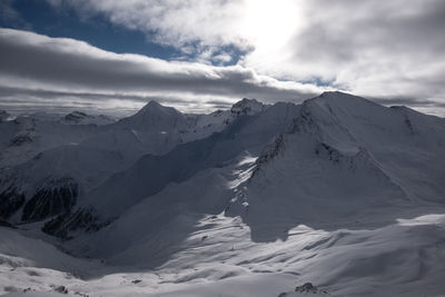 Scenic view of snow covered mountains against cloudy sky