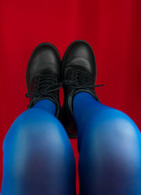 Female legs in blue tights and black boots upside down on red background. spring  fashion collection